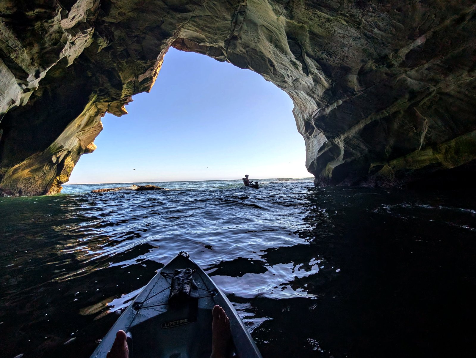 Kayakers paddling through a sea arch on California's Central Coast